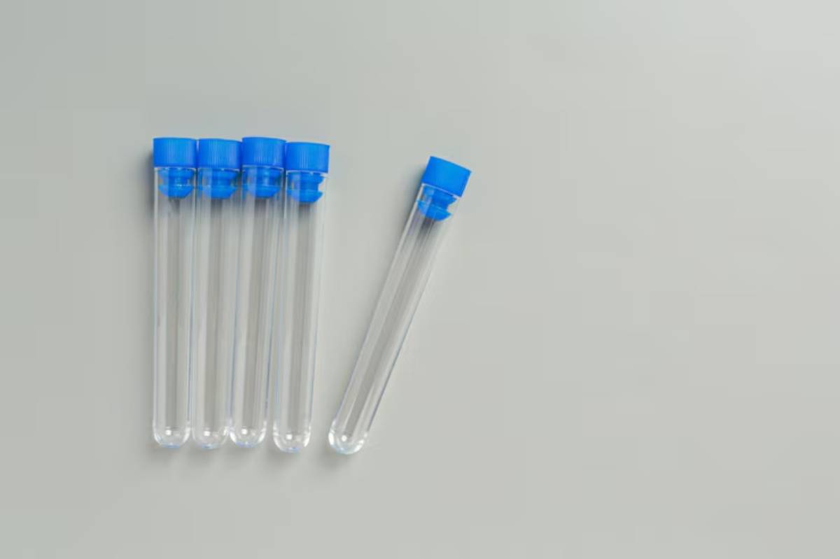 Five transparent test tubes with blue caps arranged on a light gray surface, showcasing laboratory equipment for medical testing.